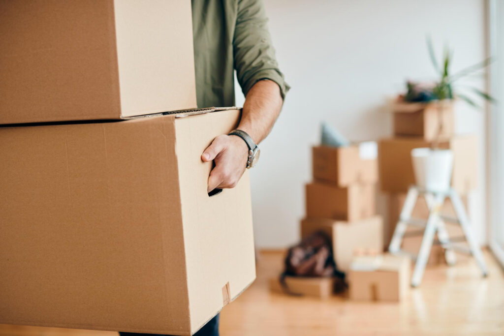 Nahaufnahme eines Mannes der Karton trägt während er in eine neue Wohnung umzieht